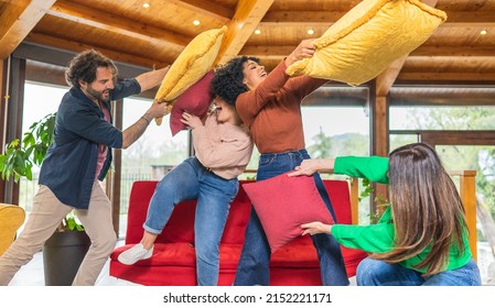 Happy multicultural friends having fun pillow fight in living room - Powered by Shutterstock