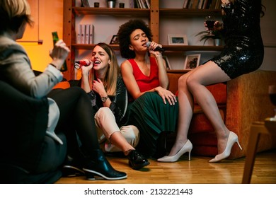 Happy multicultural friends sitting at home, laughing, singing, and having fun on karaoke night. - Powered by Shutterstock