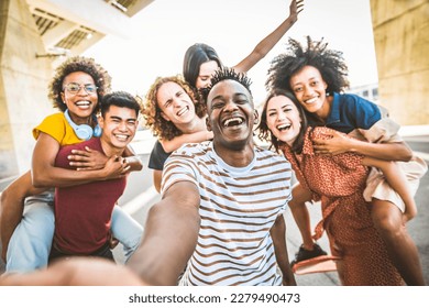 Happy multicultural friends taking selfie portrait walking on city street - University students having fun in college campus - Life style concept with guys and girls hanging out together  - Powered by Shutterstock