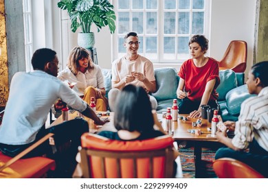 Happy multicultural hipster guys playing in gambling sitting at table with poker chips and cards, smiling diverse friends 20s spending time for together entertainment practice blackjack gaming - Powered by Shutterstock