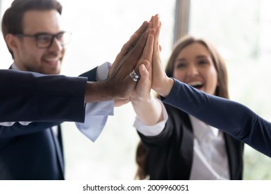 Happy multiethnic business team celebrating success. Excited office employees giving group high five, enjoying high group result, work achieve, expressing teamwork, supportive spirit. Close up