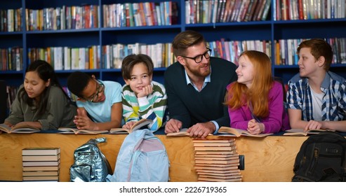 Happy multiethnic children and teacher in learning class at library. Portrait of male teacher and diverse pupils lying on floor in public library and discussing books - Powered by Shutterstock