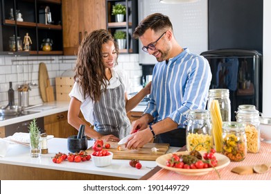 Happy Multiethnic Couple Cooking Homemade Tomato And Basil Pasta. Cooking At Home