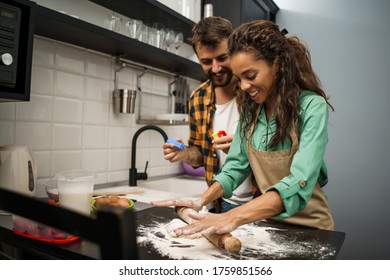 Happy multiethnic couple cooking in their kitchen. They are making cookies. - Shutterstock ID 1759851566