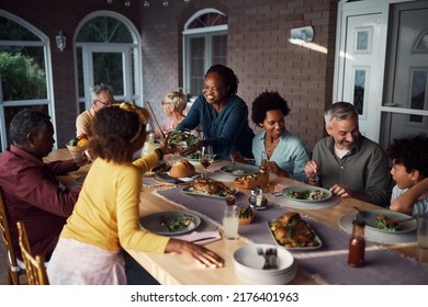 Happy Multi-ethnic Extended Family Enjoying While Gathering For Meal At Dining Table On A Patio.