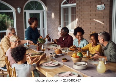 Happy Multiethnic Extended Family Enjoying While Gathering At Dining Table On A Patio. 