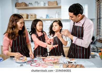 Happy Multiethnic Family Cooking Creams Cake Together In The Kitchen At Home. A Parent Teaches Daughters To Make Homemade Desserts, Enjoy Leisure Activities Time, Family Relationship Concepts.