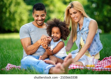 Happy multiethnic family enjoying picnic in nature - Shutterstock ID 2103663338