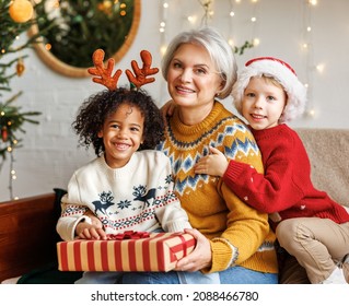 Happy multiethnic family enjoying winter holidays at home, loving grandmother with multiracial kids near xmas tree, biracial children in reindeer antlers celebrate Christmas or New Year with grandma - Powered by Shutterstock