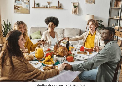 happy multiethnic family sitting at festive table praying and holding hands cheerfully, Thanksgiving - Powered by Shutterstock