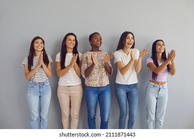 Happy Multiethnic Female Audience Giving Round Of Applause. Group Of Positive Smiling Young Women Applauding Speaker. Studio Portrait Of Five Cheerful Beautiful Ladies Standing By Wall Clapping Hands