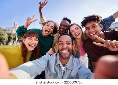 Happy multiethnic group of friends taking a selfie outdoors, having fun in sunny day. University students using phone app to take photos looking at camera. - Powered by Shutterstock