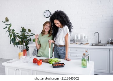 Happy Multiethnic Lesbian Couple Cooking Together In Modern Kitchen