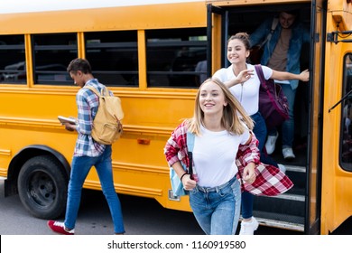 Happy Multiethnic Teen Scholars Running Out School Bus 