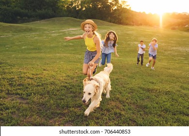 happy multiethnic teens walking with golden retriever dog in park