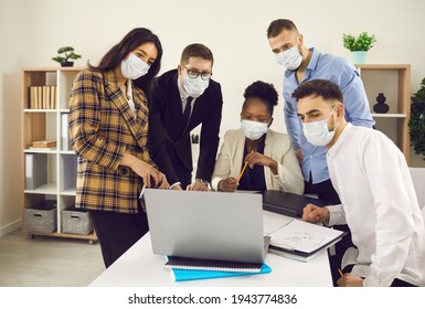 Happy Multiethnic University Students Group In Face Mask Using Laptop Computer And Internet Working Project Together Researching Information Online, Watching Webinar And Training Course After Lockdown