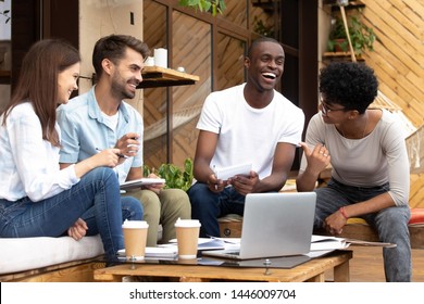 Happy multiethnic young people meet in coffee place work using laptop making notes, smiling diverse millennial friends gather in café studying together with computer have fun laughing sharing ideas - Powered by Shutterstock