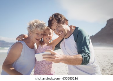 Happy multi-generated family taking selfie at beach during sunny day - Powered by Shutterstock