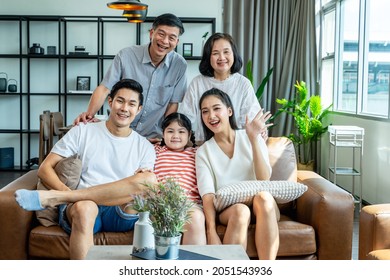 Happy Multi-generation Asian Family Sitting On Sofa At Home.