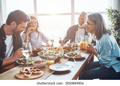 Happy multi-generation family communicating and smiling while having dinner together - Shutterstock ID 2050849856
