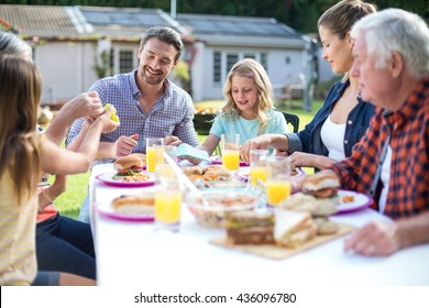 Happy Multi-generation Family Eating At Table In Back Yard