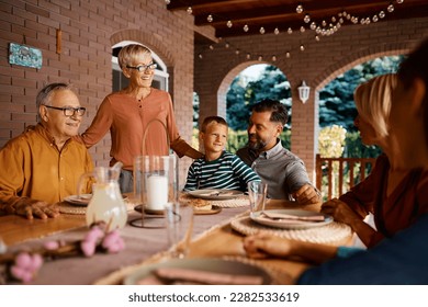 Happy multigeneration family enjoying in conversation while gathering for lunch on a terrace. - Powered by Shutterstock