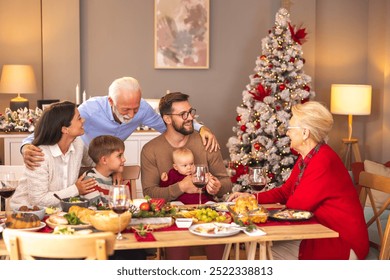 Happy multi-generation family gathered around the table, having Christmas dinner all together at home, speaking to each other and laughing - Powered by Shutterstock