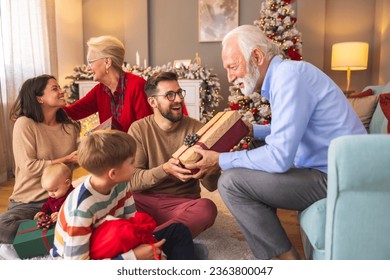 Happy multi-generation family gathered at home on Christmas day, exchanging Christmas presents and enjoying spending time together during winter holiday season