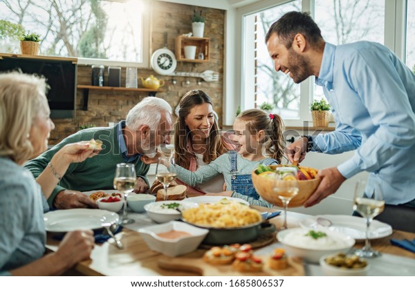 Happy multi-generation family\
gathering around dining table and having fun during a lunch.\
