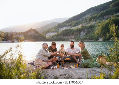 Happy multigeneration family on summer holiday trip, barbecue by lake. - Powered by Shutterstock