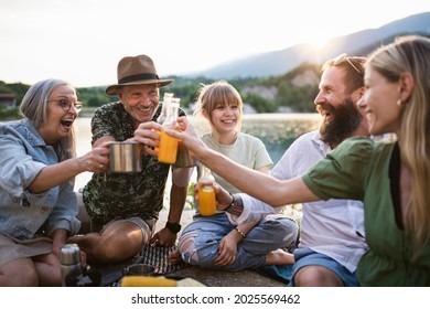 Happy multigeneration family on summer holiday trip, barbecue by lake. - Powered by Shutterstock