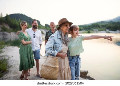 Happy Multigeneration Family On Summer Holiday, Walking By Lake.