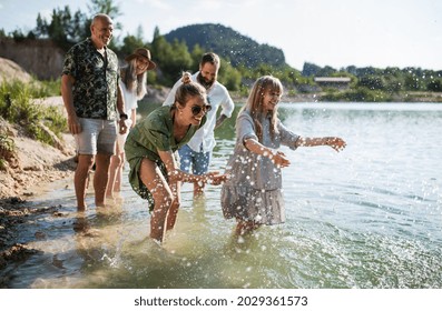 Happy Multigeneration Family On Walk By Lake On Summer Holiday, Having Fun In Water.