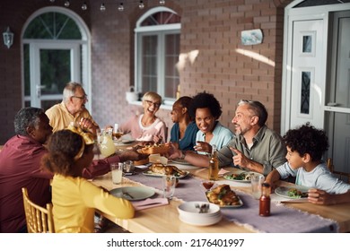 Happy Multi-generation Family Passing Food And Enjoying In Lunch At Dining Table On A Patio. 