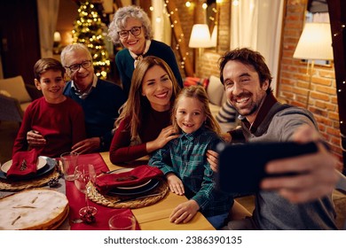 Happy multigeneration family taking selfie during Christmas dinner at dining table. - Powered by Shutterstock