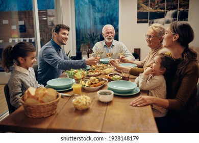 Happy multi-generation family toasting with wine during a meal in dining room. 