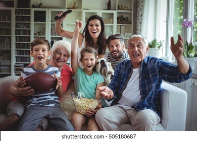 Happy multi-generation family watching soccer match on television in living room at home