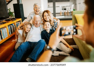 Happy multigenerational family getting their picture taken in the living room - Powered by Shutterstock