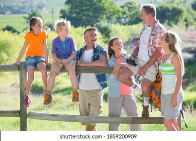 Happy Multigenerational Family Sitting On A Fence In A Rural Setting