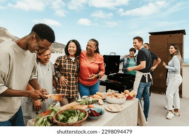 Happy multigenerational people having fun doing barbecue grill at house rooftop - Summer gatherings and food concept - Shutterstock ID 2298094479