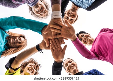 Happy multigenerational women stacking hands together after sport workout outdoor - Female friends having fun together and putting their hands on top of each other - Bright filter with shot from below
