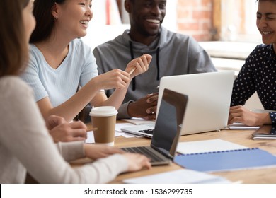 Happy multinational group of students studying gain knowledge together sit at classroom desk, take break chatting laughing, friendly warm relations between multi racial people learning process concept