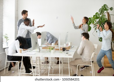 Happy multiracial business group throwing crumpled paper balls laughing having fun together in office, diverse employees doing teambuilding activity, friendly team and good relations at work concept - Powered by Shutterstock