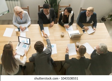 Happy Multiracial Businessmen Shake Hands At Diverse Group Meeting, Black And White Partners Handshaking After Successful Teamwork Or Team Negotiations Sitting At Conference Table, Top View Overhead