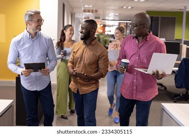 Happy multiracial businessmen walking while discussing against female colleagues at workplace. unaltered, business, teamwork and modern office concept. - Powered by Shutterstock