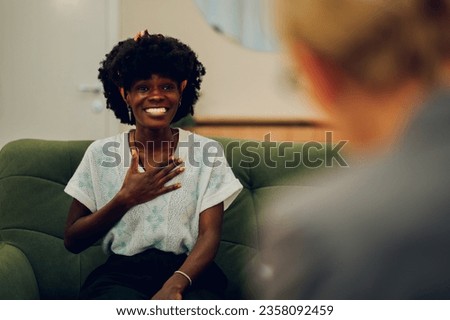 A happy multiracial client is sitting in the office with a psychotherapist and having a session. A woman is expressing her feelings during her discussion with a therapist at the mental clinic.