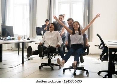 Happy multiracial colleagues group having fun together, riding on chairs in office, diverse excited office workers enjoying break, laughing, engaged funny activity, celebrating corporate success - Shutterstock ID 1245856630