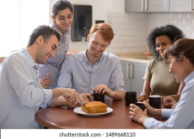 Happy Multiracial Colleagues Sit In Office Kitchen Cut Cake Celebrate Birthday Or Special Event Together, Smiling Diverse Work Team Have Fun Laugh Enjoy Tasty Pie On Coffee Break. Friendship Concept