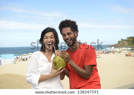 Happy multiracial couple enjoying vacation drinking coconut water on the boardwalk of Ipanema, Rio de Janeiro.
