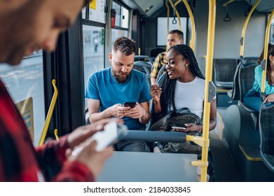 Happy multiracial couple of friends sitting in a bus and using a smartphone to message their friends who they are going to meet. Public transportation. Diverse romantic couple riding a bus. - Powered by Shutterstock